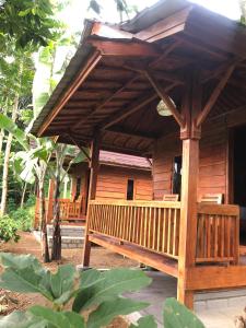 a wooden house with a porch with a roof at Serenity Lodge Tetebatu Lombok in Tetebatu