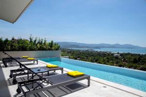 チョンモンビーチにあるSunset Estates - Samui Luxury Villasのラウンジチェア付きのプールから海の景色を望めます。