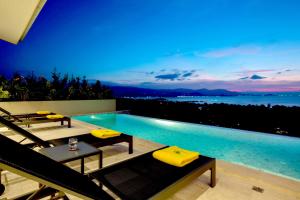 a swimming pool with yellow cushioned chairs next to a swimming pool at Sunset Estates - Samui Luxury Villas in Choeng Mon Beach