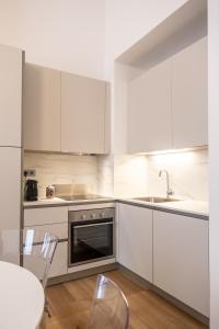 uma cozinha com armários brancos, uma mesa e um lavatório em EVE Home Collection - City Center em Trieste