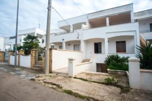 ein weißes Haus mit einem Zaun davor in der Unterkunft Casa Arianna, apartment a few steps from the sea in Marina di Mancaversa