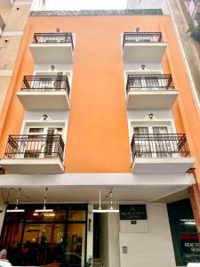 an orange and white building with balconies at Allure Athens Urban Suites in Athens