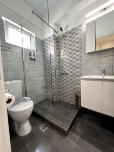 a bathroom with a shower and a toilet and a sink at Allure Athens Urban Suites in Athens
