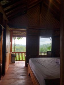 a bedroom with a bed and a balcony with a view at Serenity Lodge Tetebatu Lombok in Tetebatu