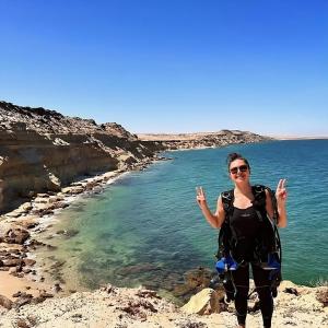 a woman standing on the rocks near the ocean at Mayorca scuba diving dakhla in Dakhla
