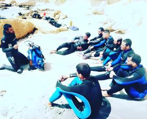 a group of men in wet suits sitting on the beach at Mayorca scuba diving dakhla in Dakhla