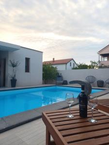 una botella de vino en una mesa junto a la piscina en Holiday&Suite Klanac, en Vir