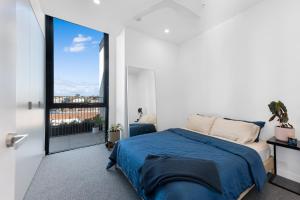 1 dormitorio con cama azul y ventana grande en Soho Penthouse - Luxury lifestyle property in Prahran, en Melbourne