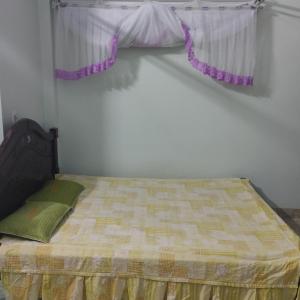 a bedroom with a bed with a window with purple curtains at Quỳnh Hà in Diện Biên Phủ