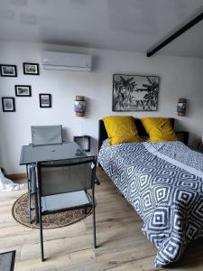 a bedroom with a bed and a desk with a laptop at L'évidence St André in Le Patelin +12 photos