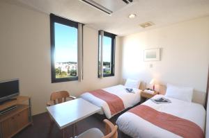 ein Hotelzimmer mit 2 Betten, einem Tisch und einem TV in der Unterkunft ArC LIFESTYLE SPACE & HOTEL in Mito