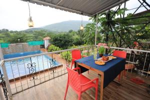 a table and chairs on a balcony with a view of the water at Sundarbagh farmhouse in Khamshet
