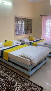 two twin beds in a room with a rug at North Star Home Stay Mysore in Mysore