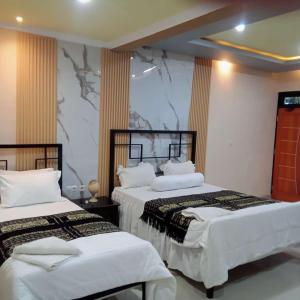 two beds in a hotel room with white sheets at Rezka Roomz Syari'ah in Ende