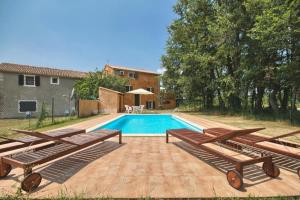 a swimming pool with three wooden benches next to a house at Ferienhaus mit Privatpool für 8 Personen ca 150 qm in Červari, Istrien Westküste von Istrien in Kanfanar