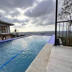 - une piscine d'eau bleue en face d'une maison dans l'établissement Veronica Guesthouse w/ Breathtaking Mountain View, à Bagolig