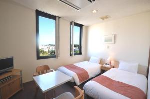 a hotel room with two beds and a table and a tv at ArC LIFESTYLE SPACE & HOTEL in Mito