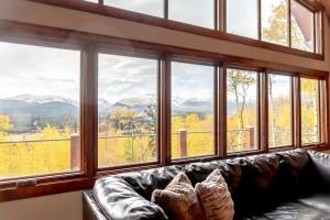 a living room with a leather couch in front of windows at Secluded Custom 5 BR with Panoramic Mountain Views in Alma