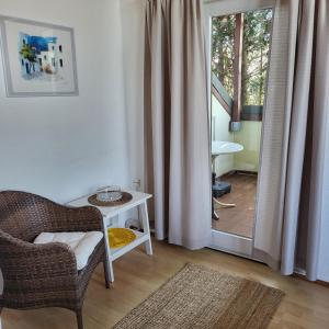 - un salon avec une chaise, une table et une porte dans l'établissement FeWo Natur & Entspannung am Bodensee, à Langenargen