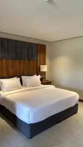 a bedroom with a large white bed with a wooden headboard at سيال 1 in Al-ʿUla