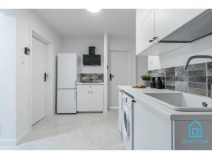 a white kitchen with a sink and a refrigerator at Crocus Room in Gdańsk