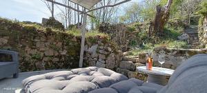 a patio with a couch and a table and a stone wall at Le Temps Suspendu in Saint-Pierreville