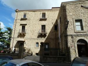 - un grand bâtiment en pierre avec des voitures garées devant dans l'établissement Sicily Rooms Enna, à Enna