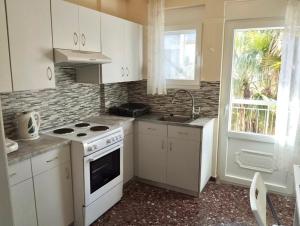 a kitchen with white cabinets and a stove and a sink at REMVI Apartment 1 in Mytilene