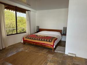 1 dormitorio con 1 cama en una habitación con ventana en VILLA FLOREANA en Puerto Velasco Ibarra