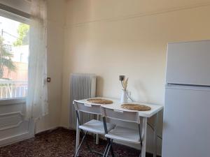 a white table with two chairs and a refrigerator at REMVI Apartment 1 in Mytilene