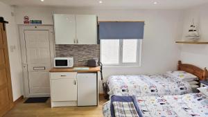 a small bedroom with a bed and a kitchen with a microwave at Four Winds Holiday Let in Nairn +7 photos