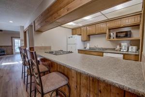 a kitchen with wooden cabinets and a counter with chairs at 3BD Retreat with Sauna and Free Bus Stop Steps Away in Breckenridge
