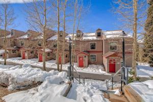 uma casa com portas vermelhas está coberta de neve em 3BD Retreat with Sauna and Free Bus Stop Steps Away em Breckenridge