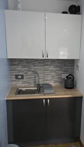 a kitchen counter with a sink and white cabinets at Four Winds Holiday Let in Nairn