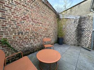 um pátio com duas mesas e cadeiras e uma parede de tijolos em IMMEUBLE ST-PIERRE - GARE 10min - HORTILLONNAGES 5min - WIFI - TV HD em Amiens