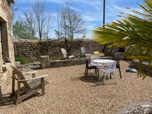 a patio with a table and chairs and a stone wall at Appartement Le camélia blanc in Corseul