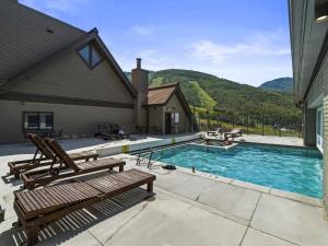 uma piscina com dois bancos de madeira ao lado de uma casa em Cozy 1BR Resort Living with Ski Lift Seconds Away em Park City