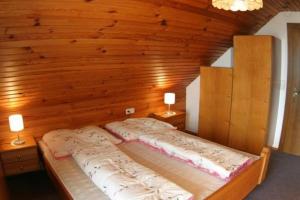 duże łóżko w pokoju z drewnianymi ścianami w obiekcie Ferienwohnung für 7 Personen ca 70 qm in Bleiburg, Kärnten Unterkärnten w mieście Bleiburg