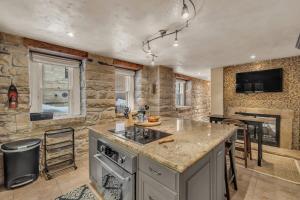 a kitchen with an island in a room with a stone wall at Rustic 2BR Steps from Main St in Park City