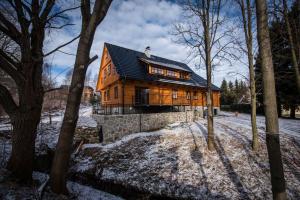una casa in legno con tetto nero nella neve di Roubenka u sjezdovky - Bělá pod Pradědem – Filipovice a Filipovice