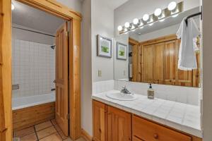 e bagno con lavandino, specchio e vasca. di Luxurious 2BDR in Deer Valley with Hot Tub a Park City