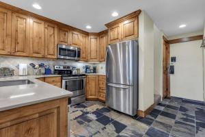 a kitchen with wooden cabinets and a stainless steel refrigerator at Ski In Ski Out 3BR Steps from Ski Resort in Park City +17 photos