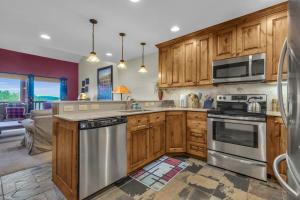 a kitchen with wooden cabinets and stainless steel appliances at Ski In Ski Out 3BR Steps from Ski Resort in Park City