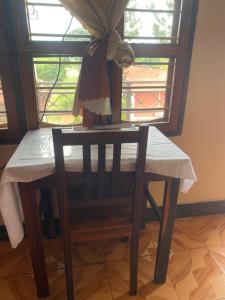 een houten tafel met een stoel in een kamer bij Nzimano Hostel in Kigoma