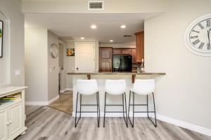 una cocina con taburetes blancos en una barra de cocina en Villa Desert Ridge condo en Phoenix