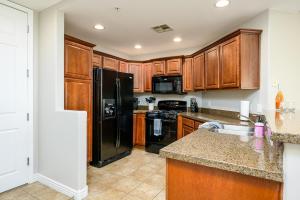 a kitchen with wooden cabinets and a black refrigerator at Villa Desert Ridge condo in Phoenix