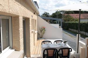 a white table with chairs and an umbrella on a patio at La Chaloupe gites de mer in Jullouville-les-Pins