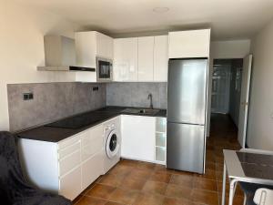 a kitchen with white cabinets and a stainless steel refrigerator at Granada I Apartment- Patalavaca in Patalavaca