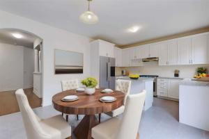 a kitchen and dining room with a wooden table and chairs at 4-Bedroom Serenity Retreat - Comfort & Style in Brampton