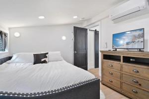 a bedroom with a bed and a dresser with a flat screen tv at Stylish Downtown 2BD Walk to Chairlifts in Park City